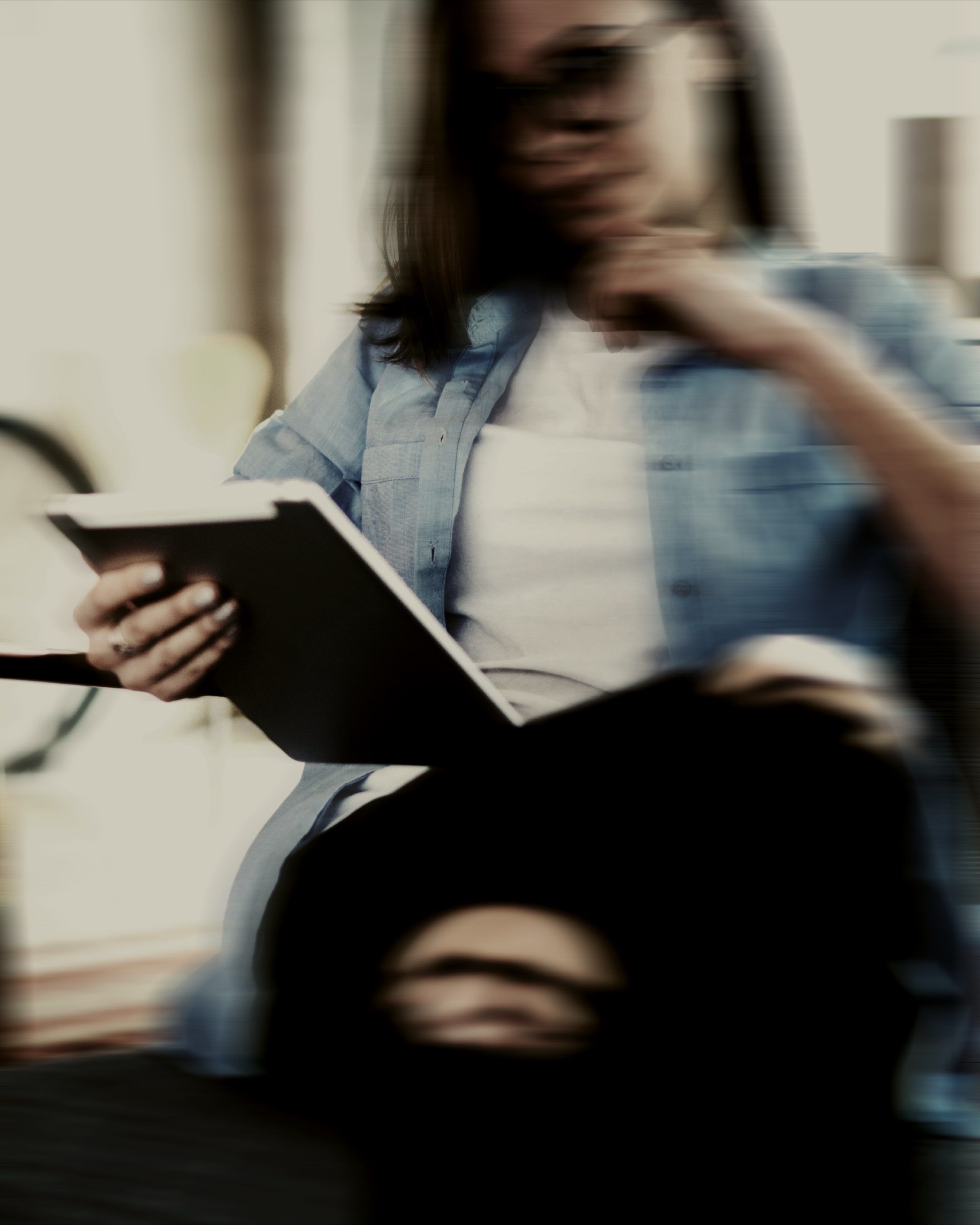 Person reading a file, leaning against a window